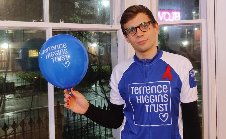 Fundraiser Aaron in Terrence Higgins Trust cycling top and holding balloon