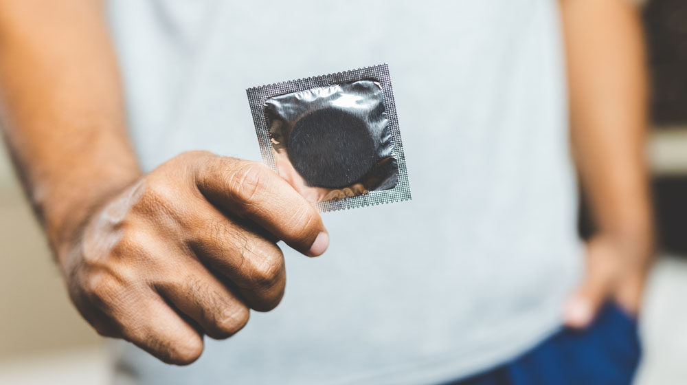 Condom in silver packet held in a hand