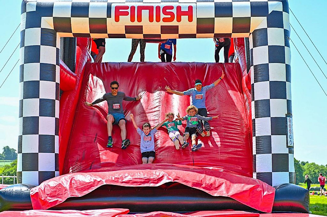 Finish line of the Inflatable 5K with participants sliding down a bouncy ramp