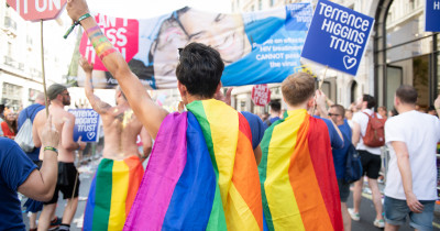 Pride marchers wearing rainbow cloaks