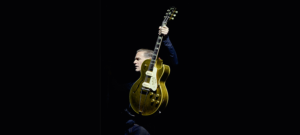 Bryan Adams holding up guitar Bryan Adams holding up guitar