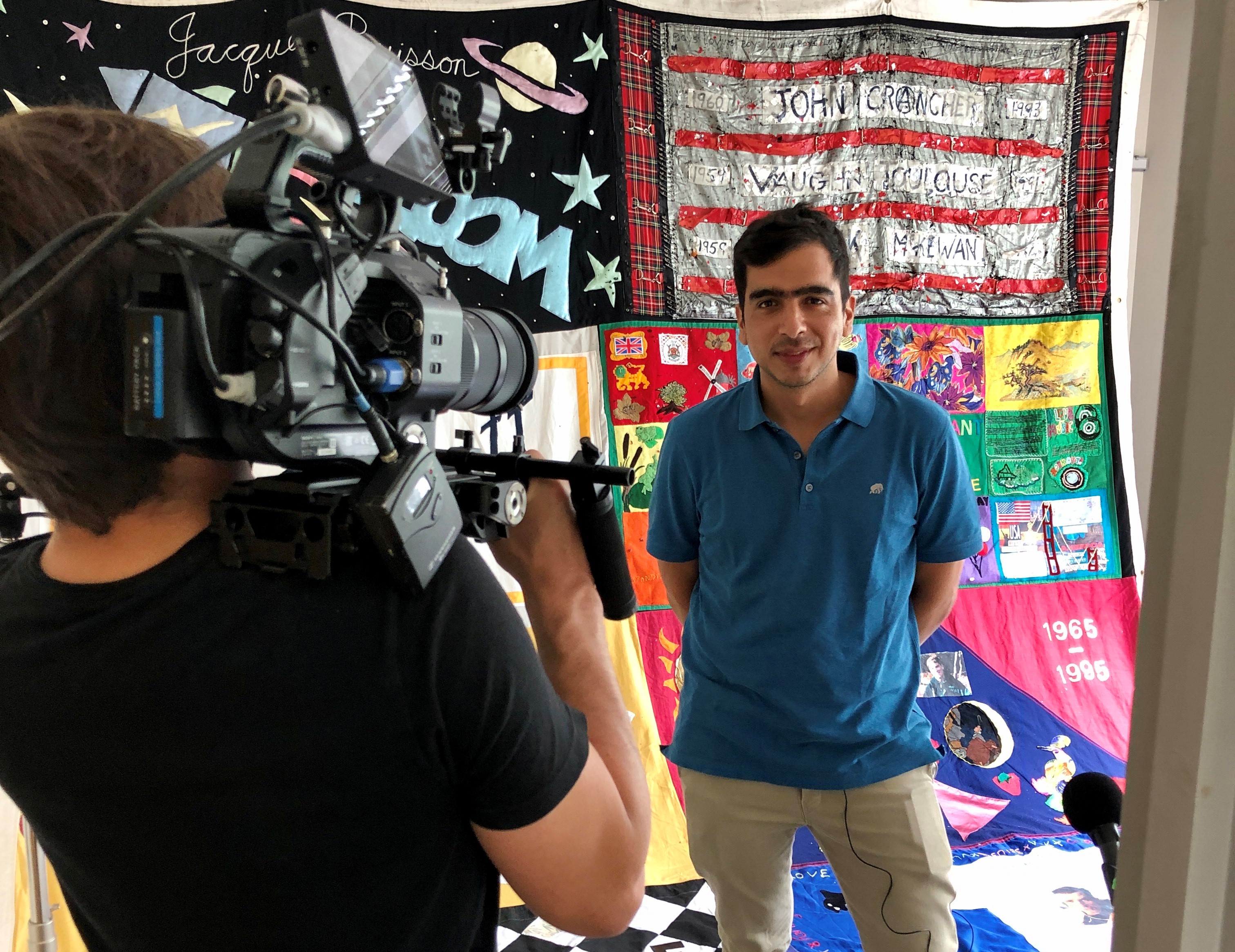 Jose of Fast Track Cities resenting to a video camera in front of a quilt