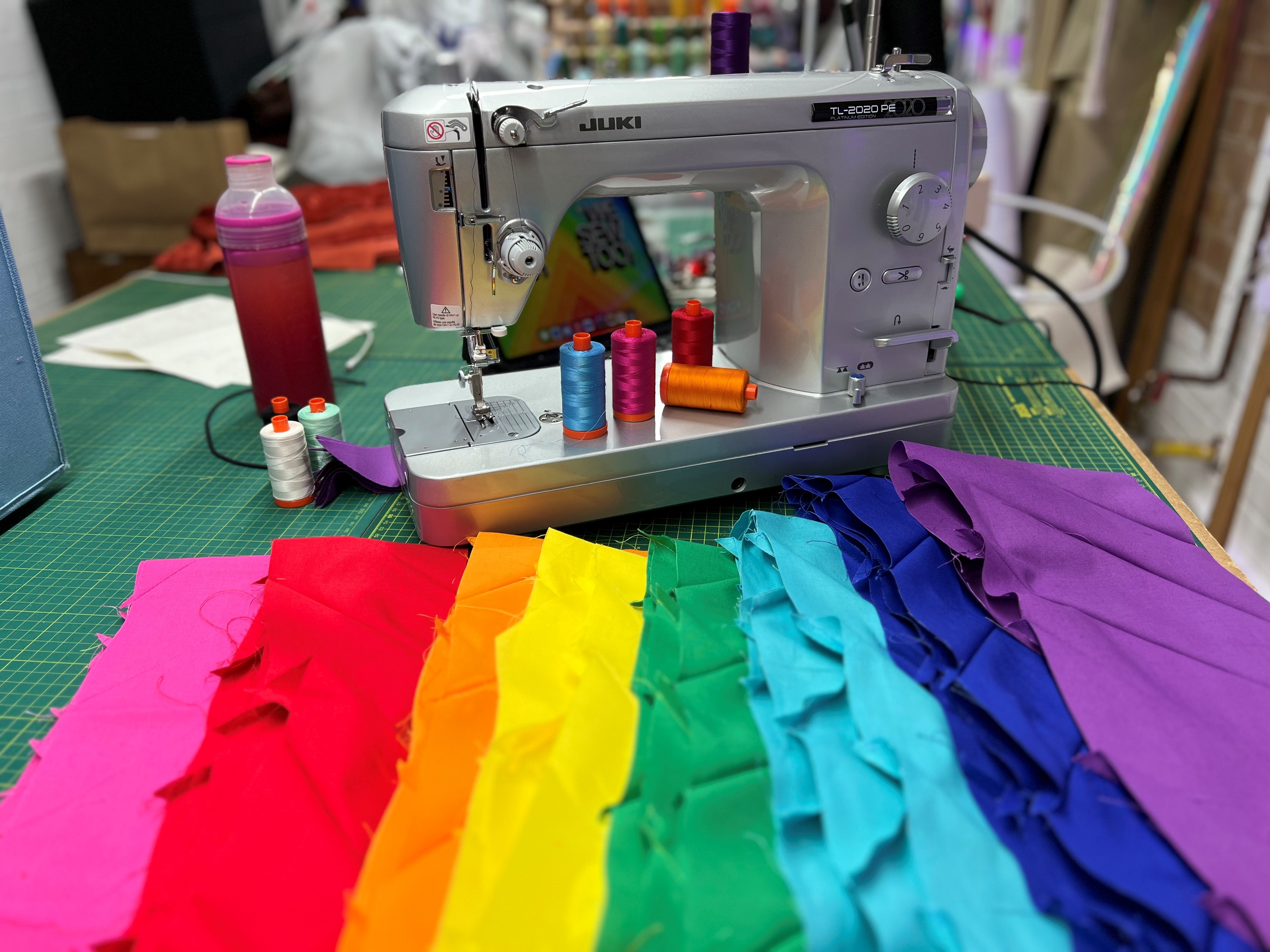 Terry Higgins Memorial Quilt panel: a rainbow of fabric next to sewing machine