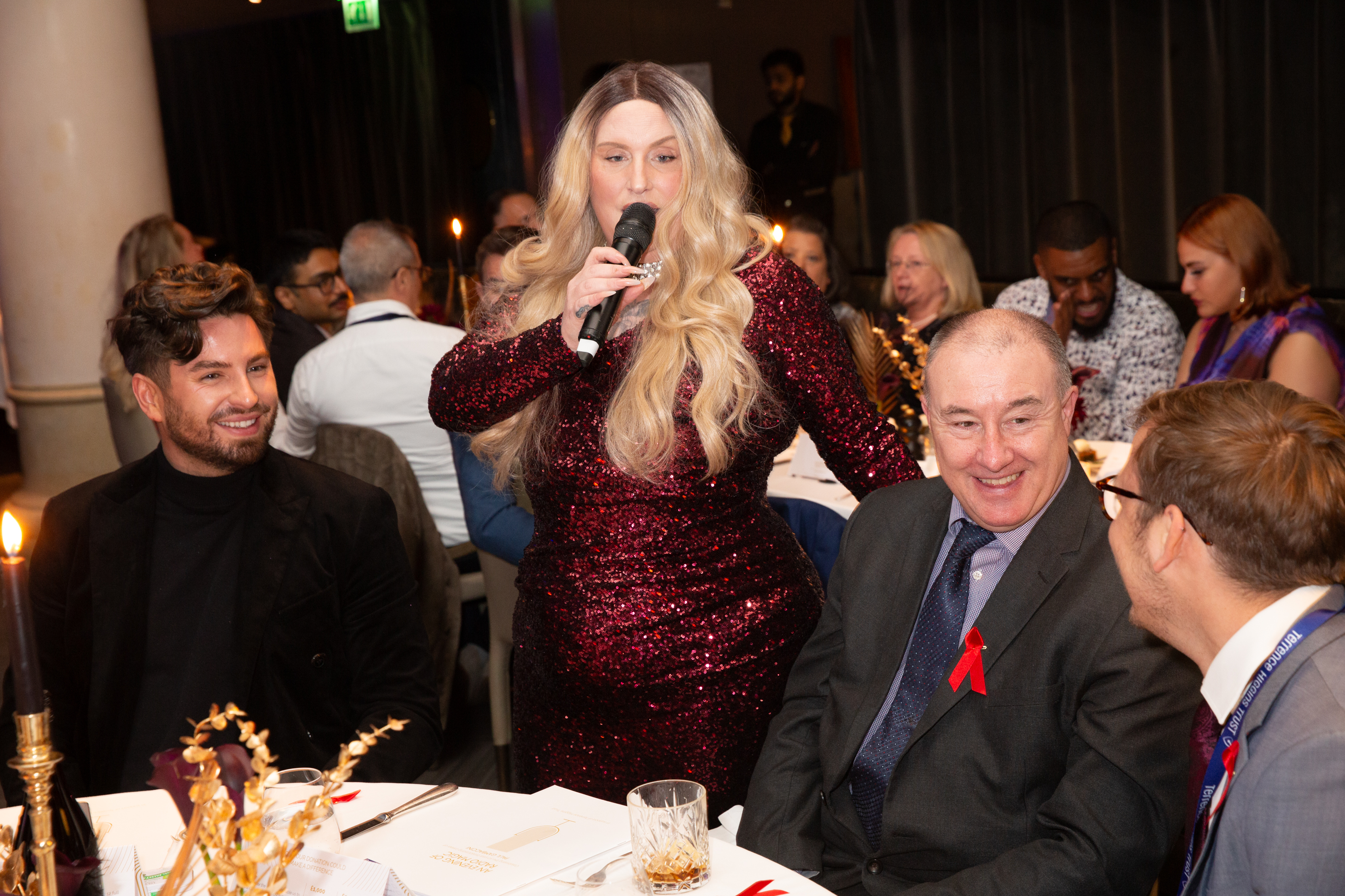 Attendees at tables with woman and microphone