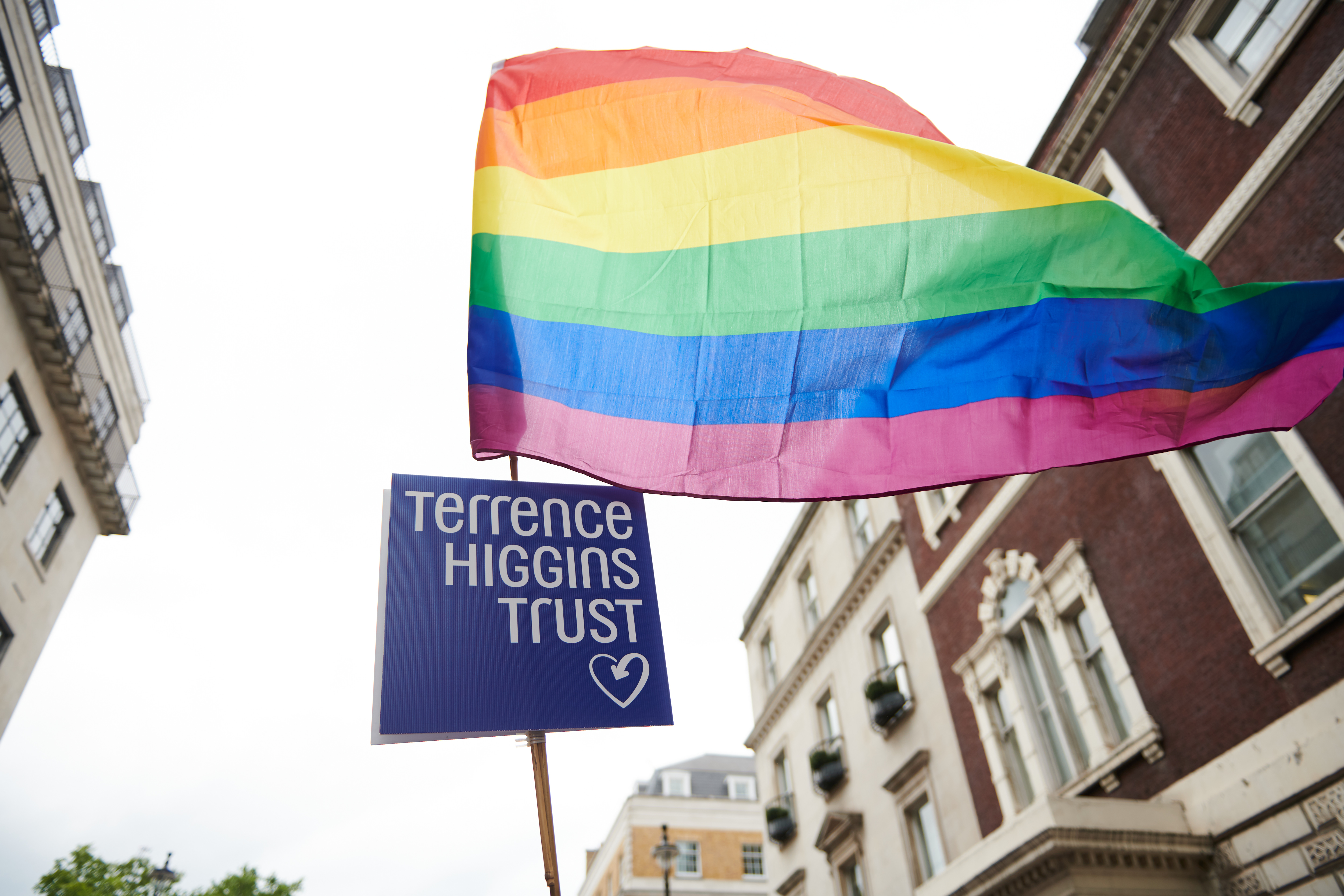 Upshot shot of pride flag and Terrence Higgins Trust logo on a big pole
