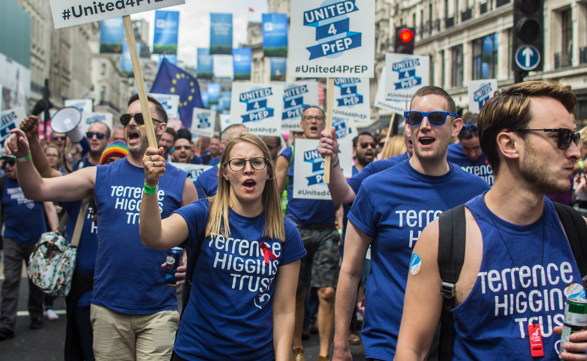 Terrence Higgins Trust staff and volunteers with banners and signs marching during Pride