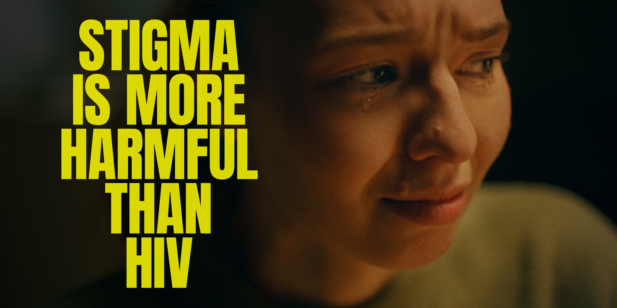 Close up of crying woman's face, with the slogan "stigma is more harmful than HIV"