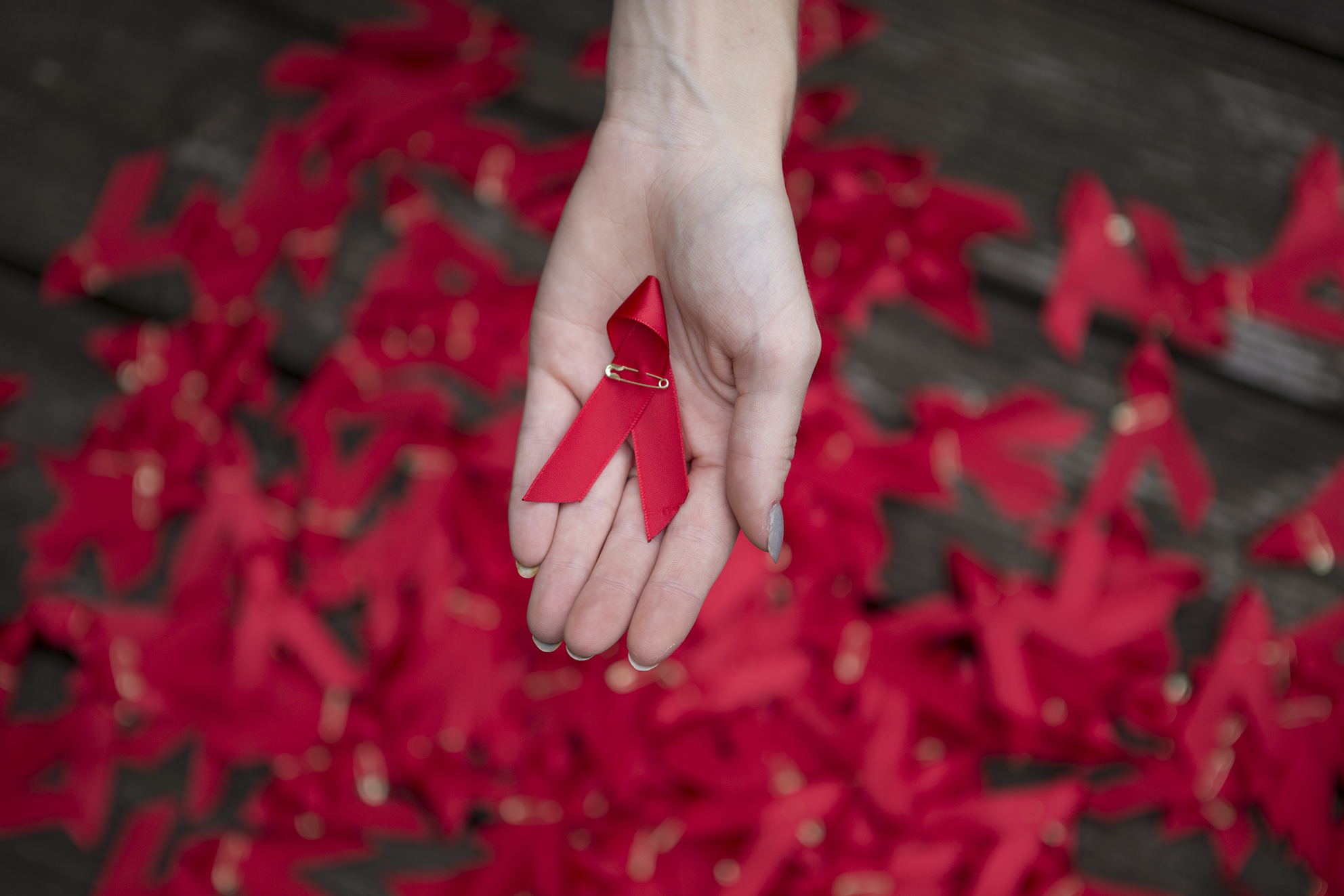 One hand holding one red ribbon One hand holding one red ribbon