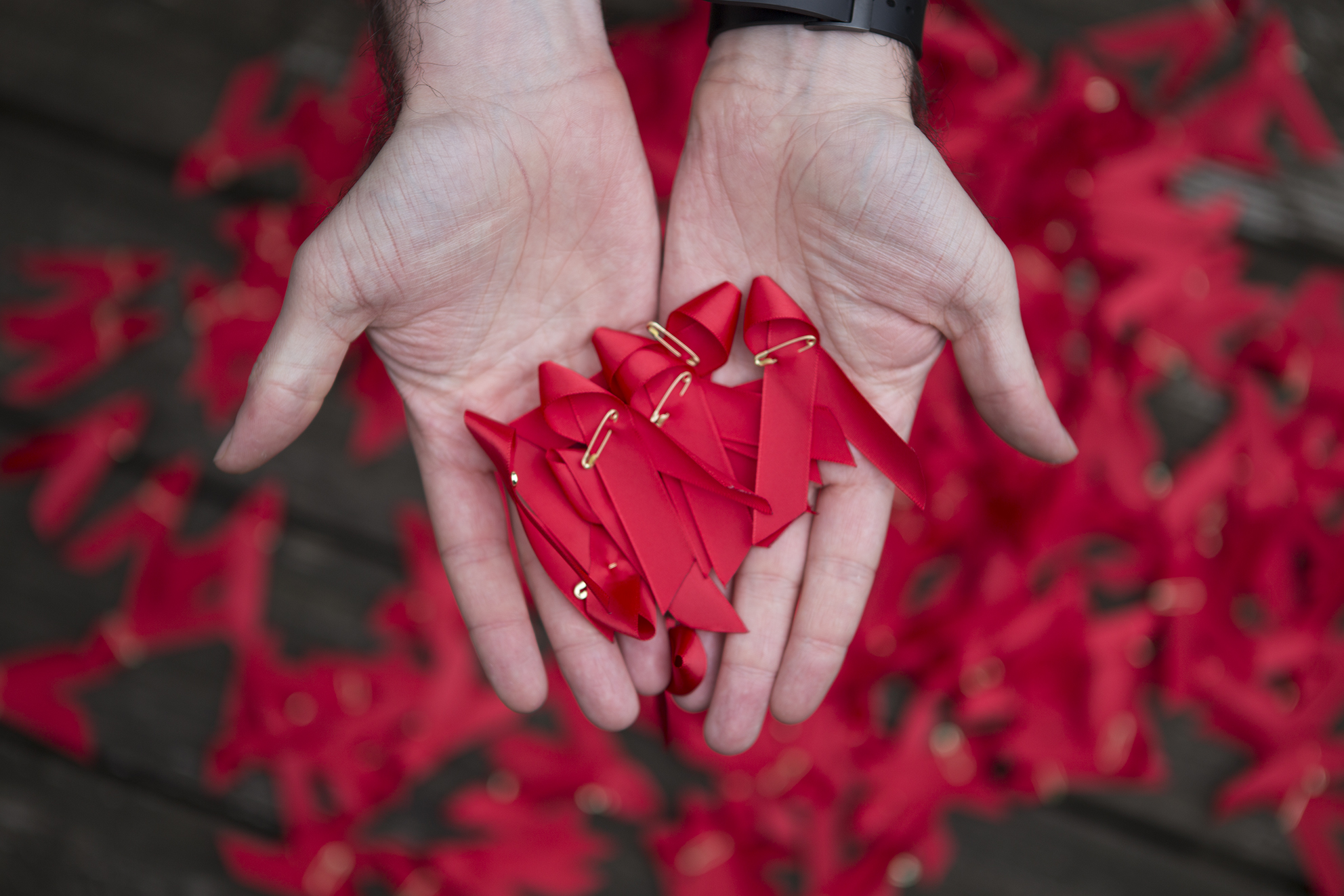 A hand holding red ribbons