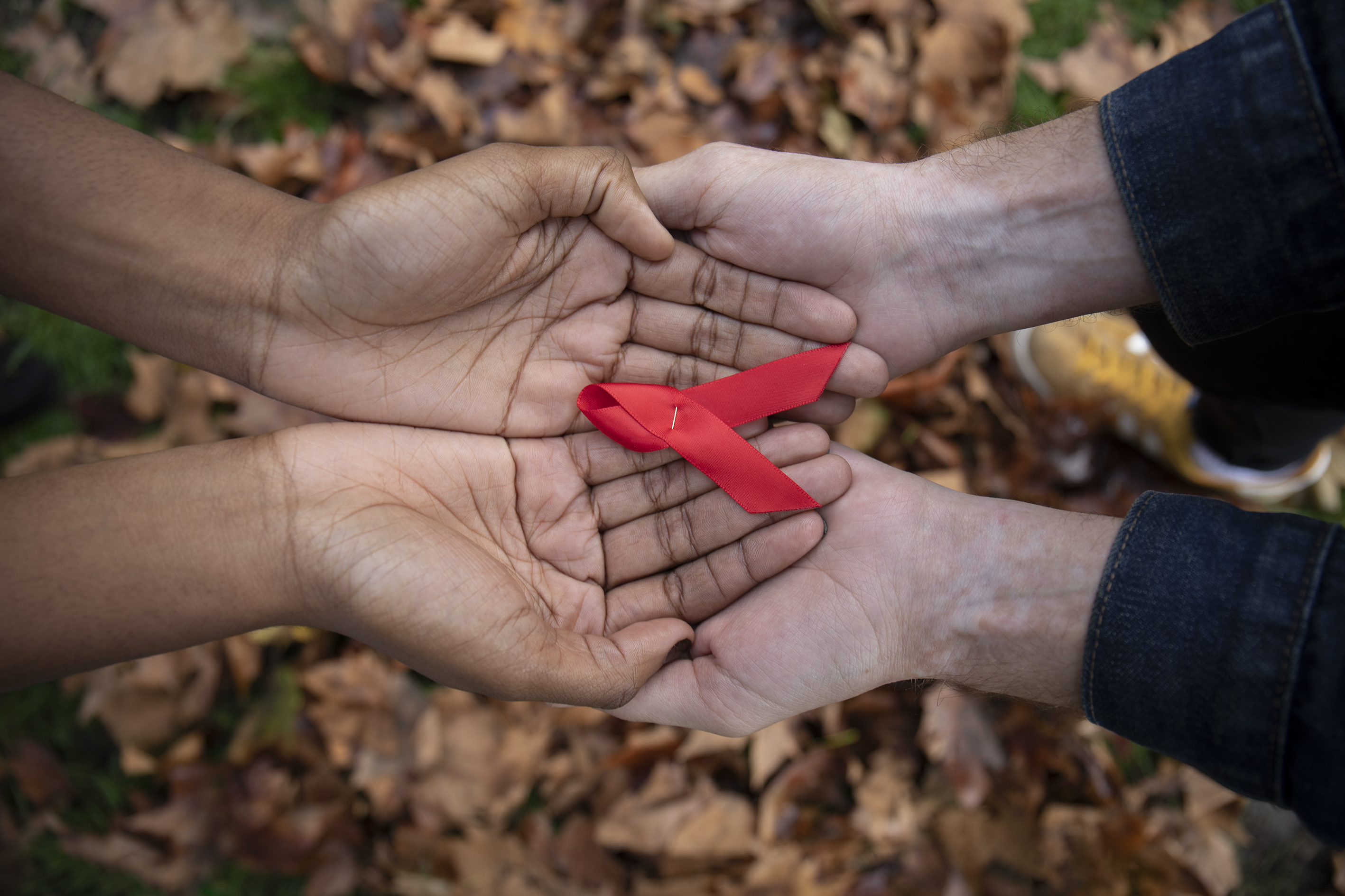 Red ribbon held by four hands