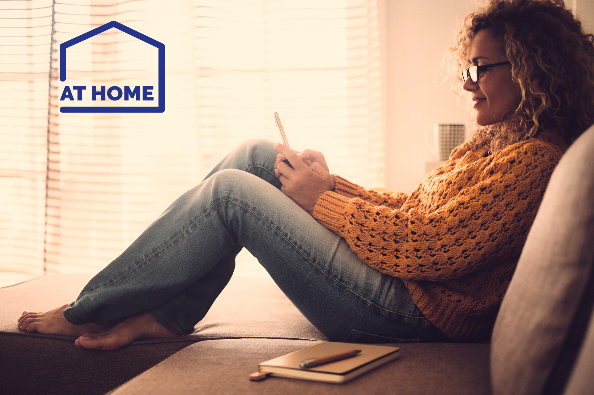 Women reading her phone sitting on a bed - At Home