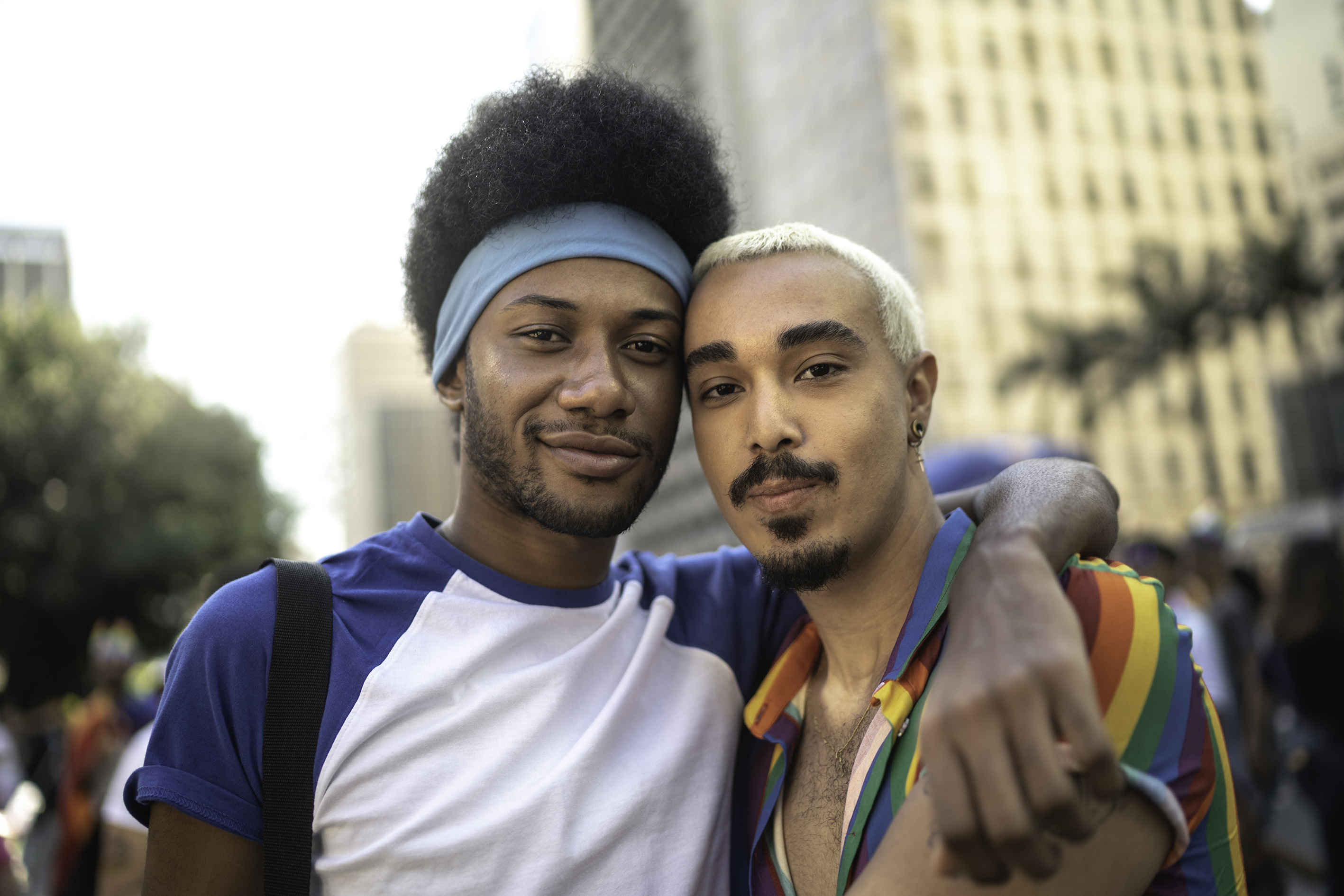 Two men, one arm round other, pride rainbow outfit Two men, one arm round other, pride rainbow outfit