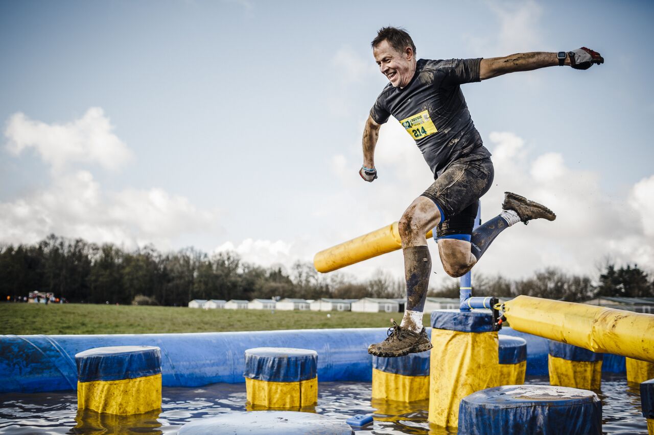 Rough Runner man leaping over water obstacle Rough Runner man leaping over water obstacle