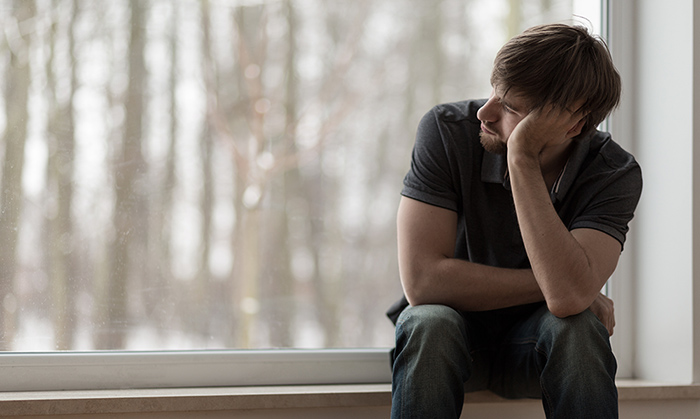 Man sitting on windowsill, thinking Man sitting on windowsill, thinking