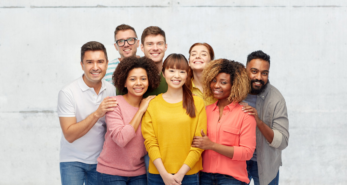 Stock group of eight people smiling in front of white wall