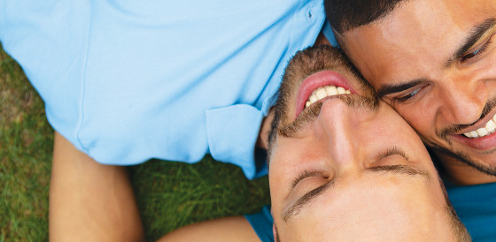 Two men lying together on grass