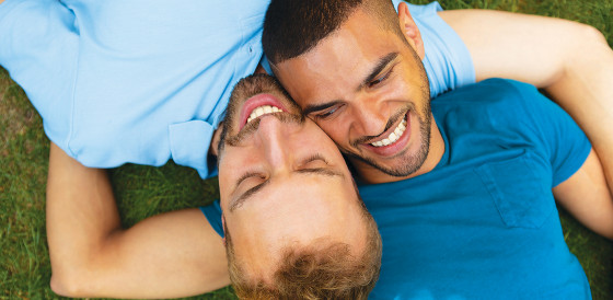 Two men lying together on the grass and smiling