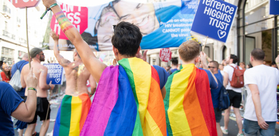 Pride marchers wearing rainbow cloaks