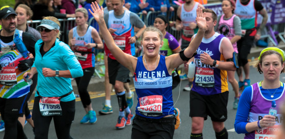 Helena running the London Marathon with arms up in celebration