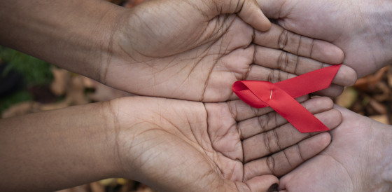 Red ribbon held by four hands Red ribbon held by four hands