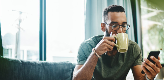 Man sipping a drink and looking at his phone