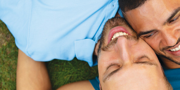 Two men lying together on grass