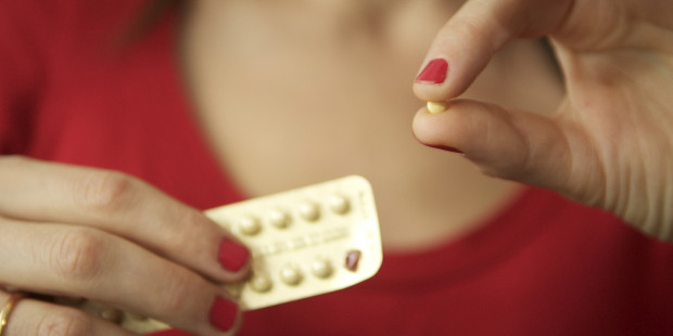 A woman holding a pill taken from a packet