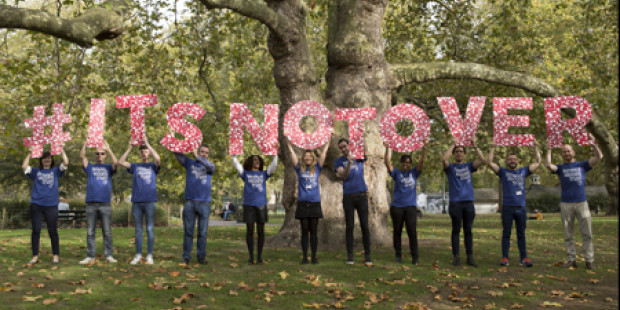 People holding World AIDS Day slogan 'It's not over' in giant letters