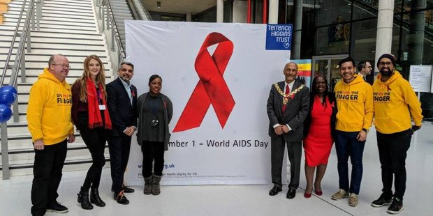 People standing either side of a red ribbon sign in an office building