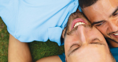 Two men lying together on grass