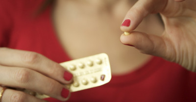 A woman holding a pill taken from a packet
