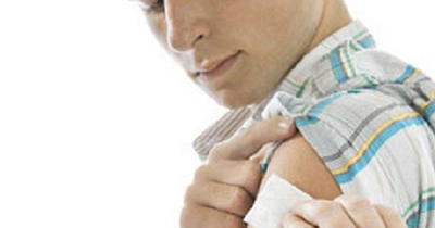 Man holding patch on arm after vaccination