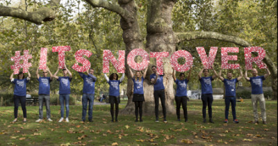 People holding World AIDS Day slogan 'It's not over' in giant letters