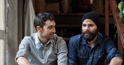 Two men sitting on a step in discussion.