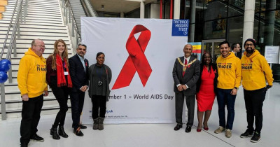 People standing either side of a red ribbon sign in an office building