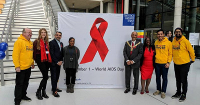People standing either side of a red ribbon sign in an office building