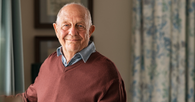 An older man faces the camera smiling