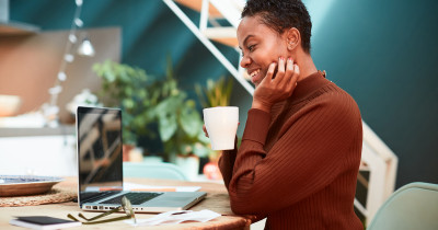 Woman with a drink look at a Macbook laptop