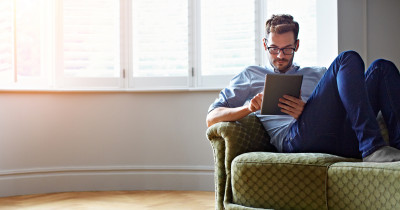 Man on sofa reading on a tablet