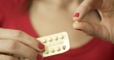 A woman holding a pill from a blister pack