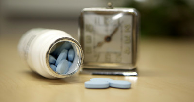 Blue pills next to an alarm clock