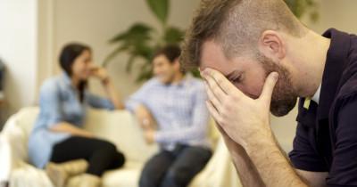 Man with head in his hands in front of couple of sofa