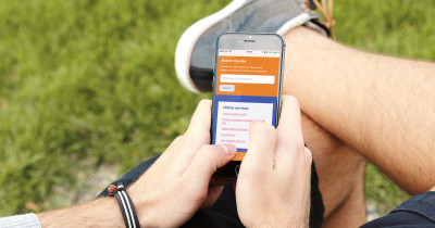 Someone using Terrence Higgins Trust's website on their iphone in a park