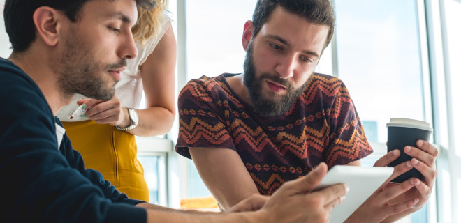 Man showing his tablet to a friend.