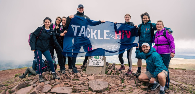 Gareth Thomas and other mountain climbers at the summit with a "Tackle HIV" banner.