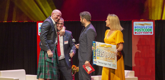 Gareth Thomas on stage with Ian Green at People's Postcode Lottery Charity Gala getting Postcode Hero award