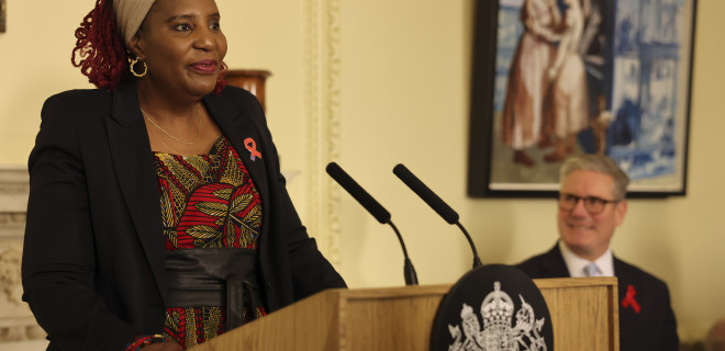 Memory Sachikonye delivering a speech with Keir Starmer in the background.