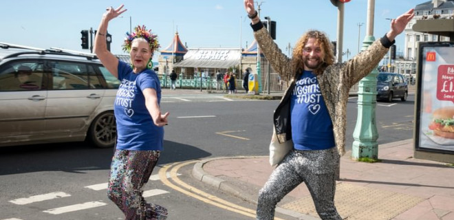 Two people in Terrence Higgins Trust t-shirts joyfully posing in Brighton.