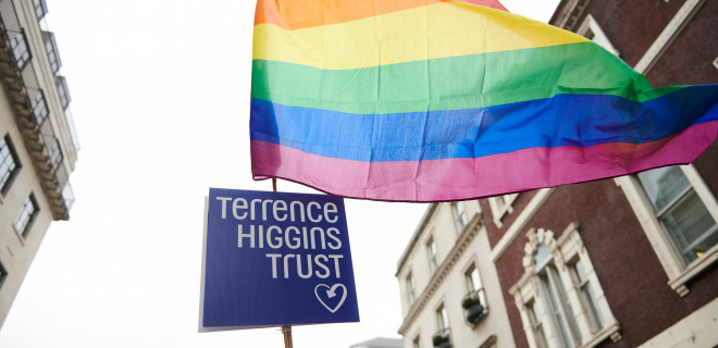 Upshot shot of pride flag and Terrence Higgins Trust logo on a big pole