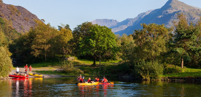 People in kayaks on a lake with mountainous Welsh landscape behind them